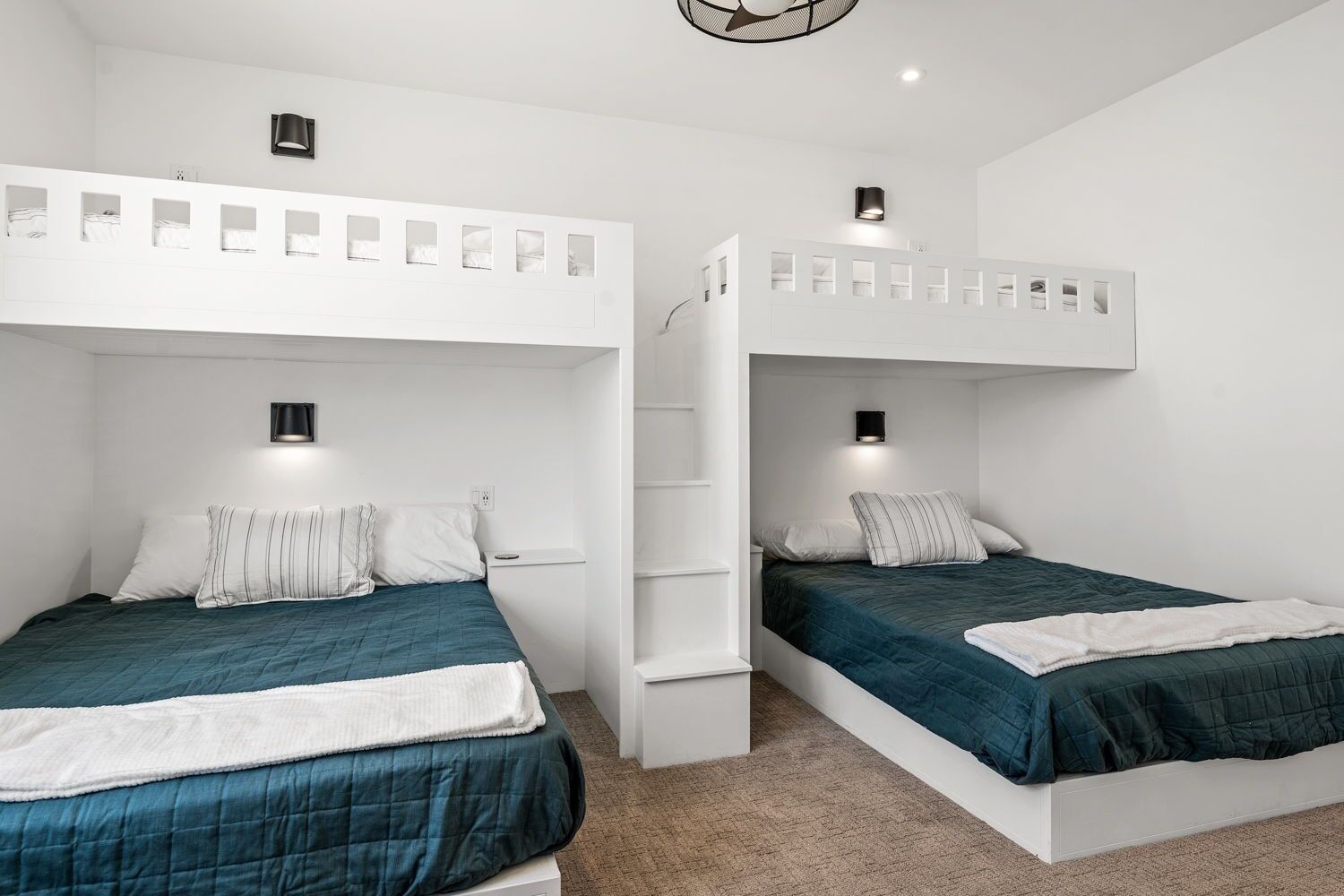 Une chambre avec des lits superposés, des murs blancs et des étagères intégrées.