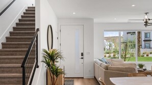 Een modern interieur met een trap, een bank, een eettafel en uitzicht op het buiten.