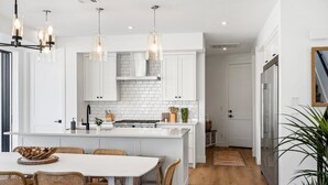 Een moderne keuken met witte kasten, een centraal eiland en hanglampen.