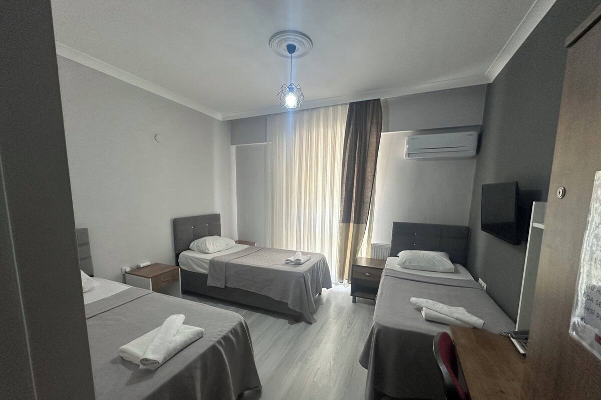 A hotel room with two beds, a flat-screen TV, an air conditioning unit, and a wooden desk.