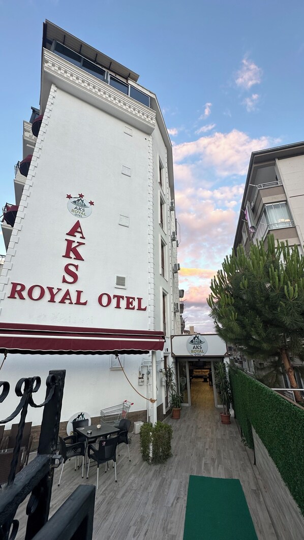 The exterior of the Aks Royal Hotel with a clear sky and a sunset.