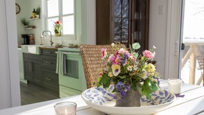 Ett matbord med en blomsterdekoration i mitten, ett ljus och ett glas vatten.