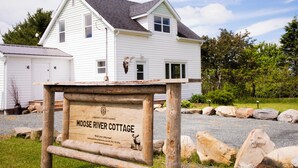 Ett vitt hus med en skylt som visar att det är Moose River Cottage.