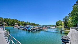 Een jachthaven met aangemeerde boten, een houten steiger en een rustig waterlichaam omringd door groen.