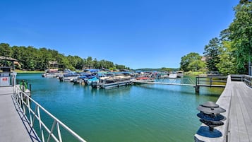 A marina with docked boats, a wooden pier, and a calm water body surrounded by greenery.