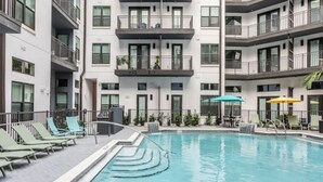 A modern building with a swimming pool, multiple balconies, and outdoor seating areas.