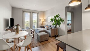 A modern living room with a dining area, a sofa set, a large potted plant, and a television.