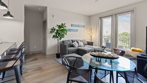 Una sala de estar moderna con un sofá gris, una mesa de comedor de vidrio y una planta en maceta.