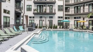 Un edificio moderno con piscina, varios balcones y zonas de estar al aire libre.