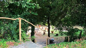Eine Holztreppe führt zu einem überdachten Bereich mit Sitzgelegenheiten und Blumentöpfen.
