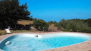 Ein rechteckiger Pool mit Backsteinrand, umgeben von Rasen und Bäumen.