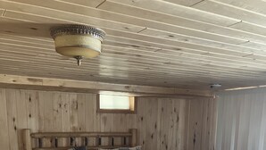 Una habitación de cabaña de madera con una cama, un aparador y una lámpara en el techo.
