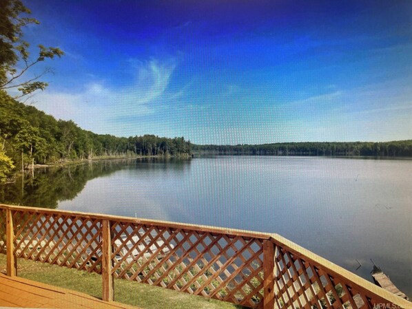 A calm lake with a wooden deck and lattice railing.