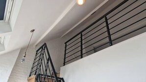 A modern interior with a staircase, a light bulb hanging from the ceiling, and a window with blinds. - Zennon II - Feel Good (Geraardsbergen)