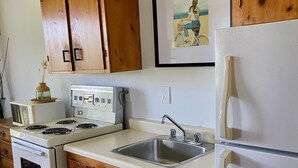 Une cuisine avec des meubles de rangement en bois, une cuisinière, un évier et un réfrigérateur.