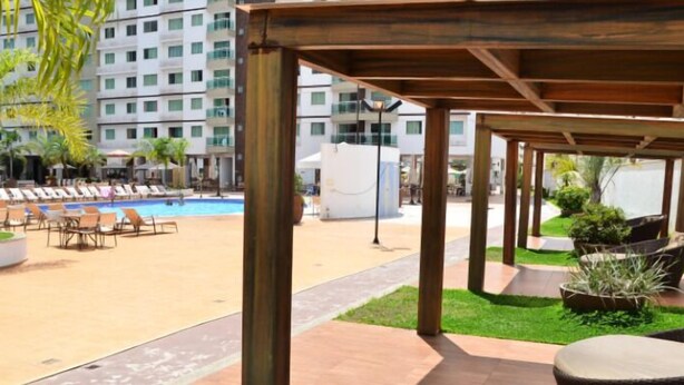 Zona junto a la piscina con sillones de descanso y una zona de estar cubierta.