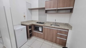 Una cocina compacta con microondas integrado, un lavamanos y un refrigerador pequeño.