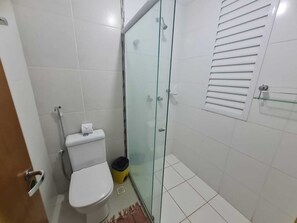 A bathroom with a toilet, a glass shower enclosure, and a towel rack.