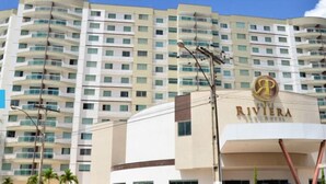 Un hotel de diseño moderno, con un llamativo letrero 'Riviera' y una estructura de varios pisos con balcones.