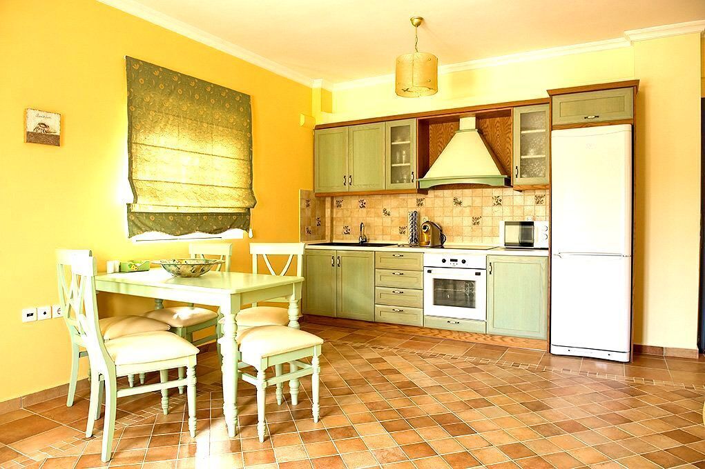 Una cocina con una mesa de comedor, sillas, estufa, lavaplatos y refrigerador.