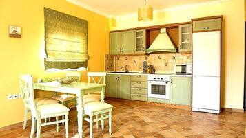 Una cocina con una mesa de comedor, sillas, estufa, lavaplatos y refrigerador.