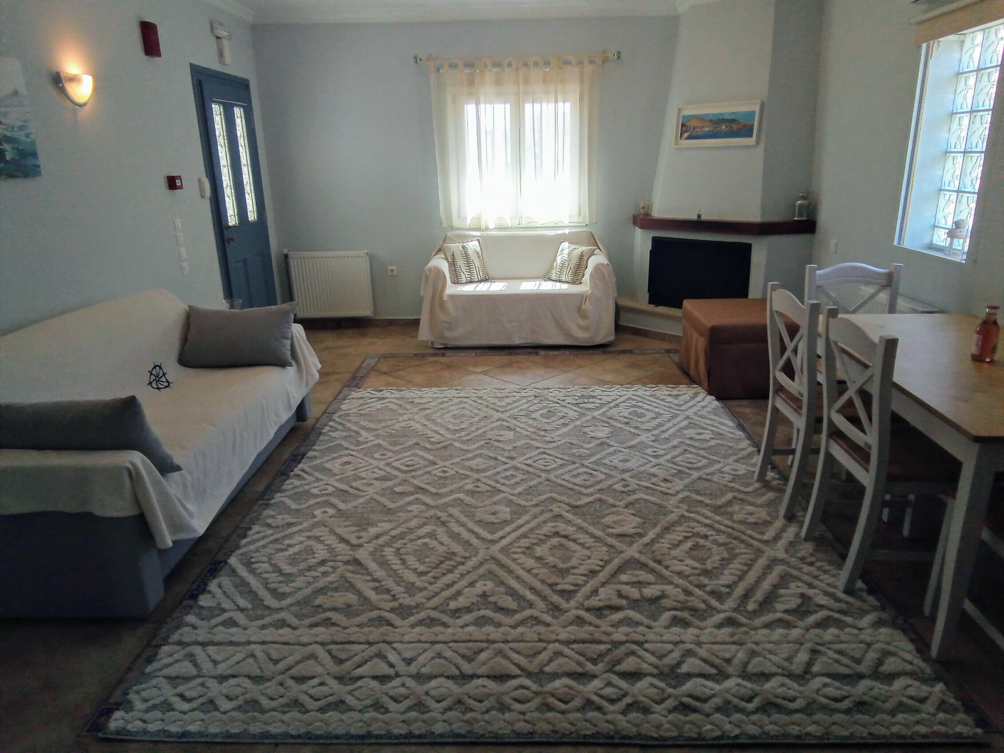 A living room with a sofa, a small table, a rug, and a window with curtains.