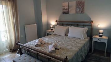 A neatly made bed with white linens and rolled towels, a wooden headboard, bedside tables with lamps, and artwork on the wall.