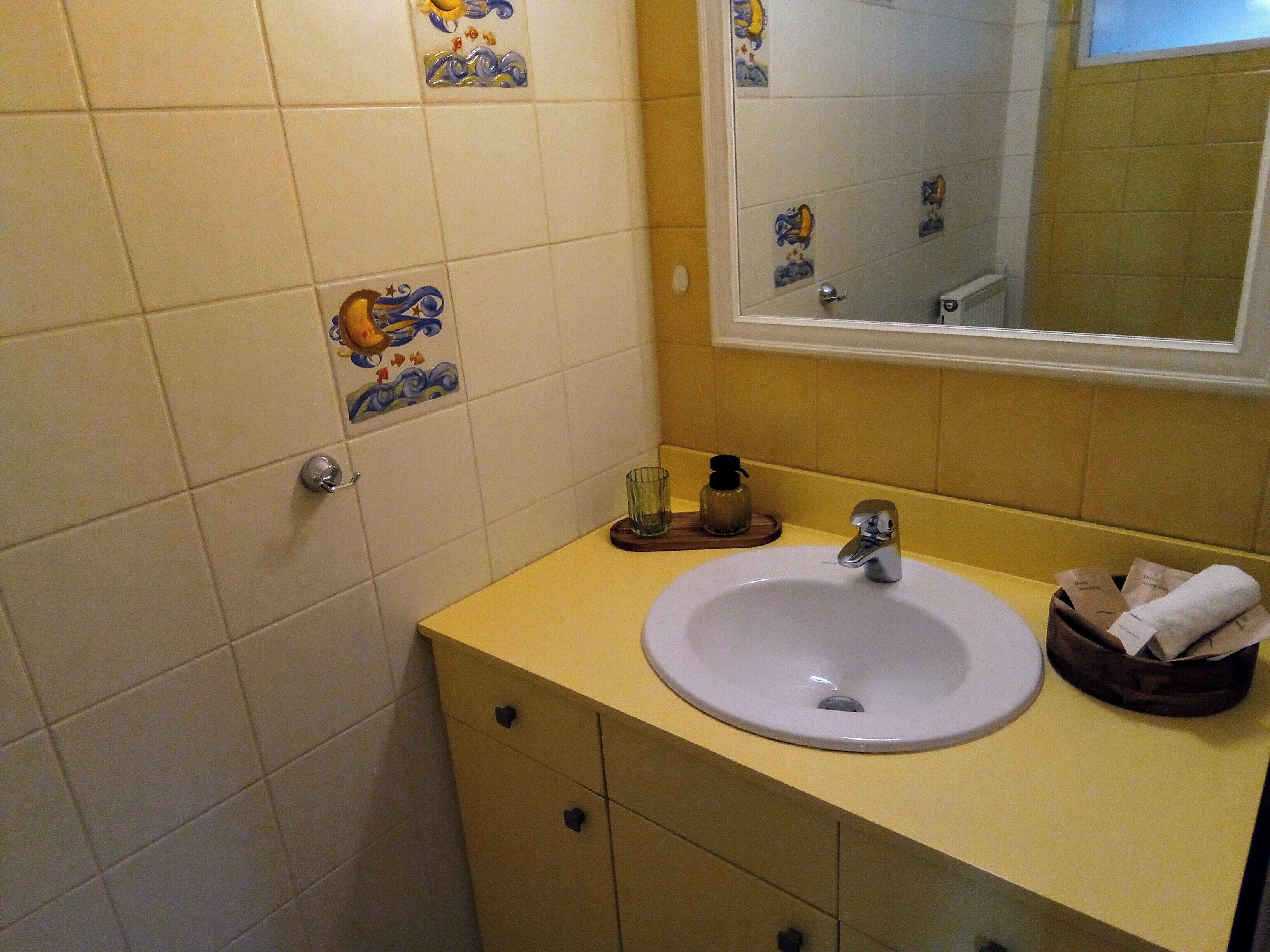 Un baño con lavamanos, espejo y azulejos decorativos.