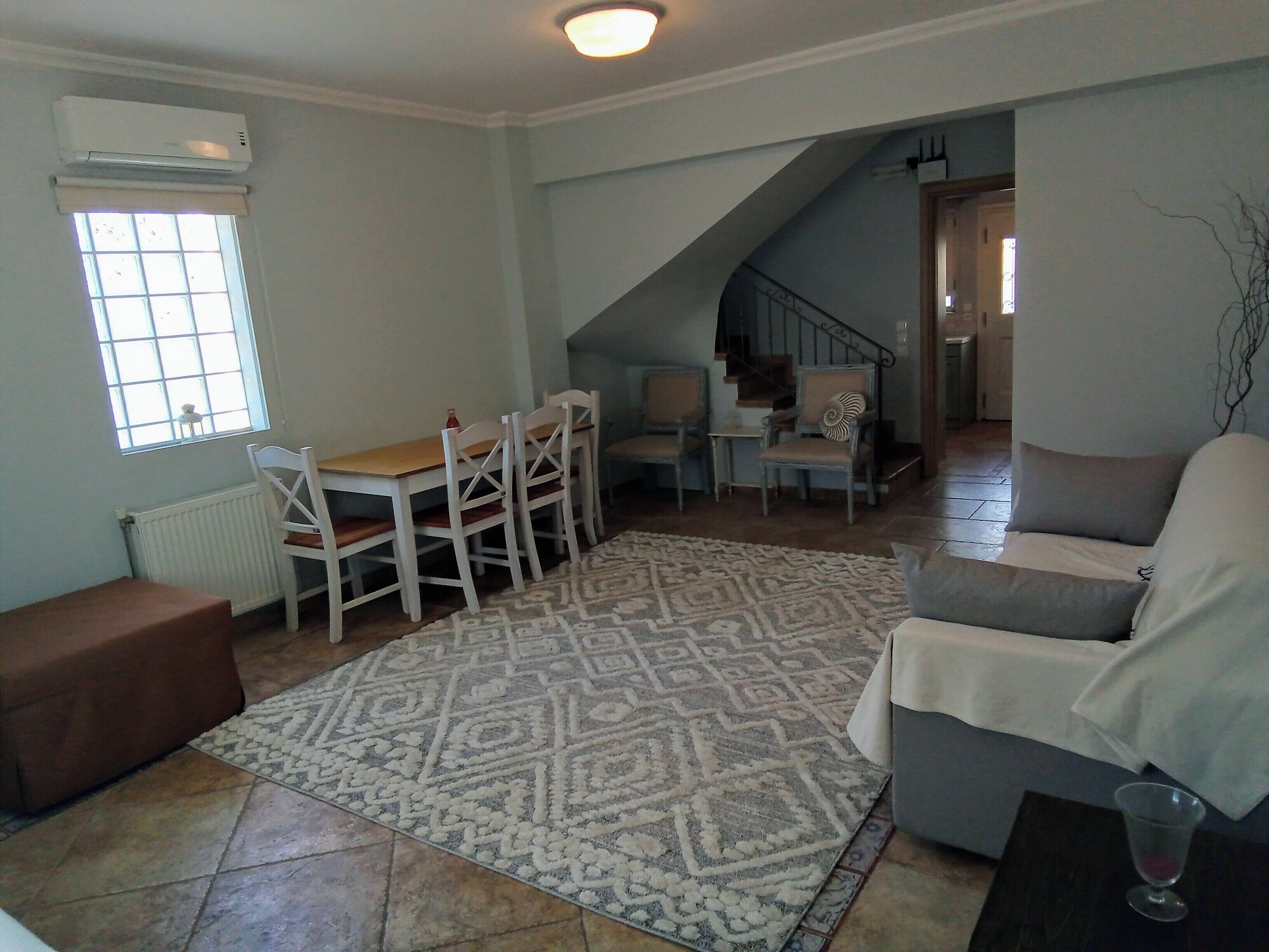 A living room with a dining area, a staircase, and a view of the outside.