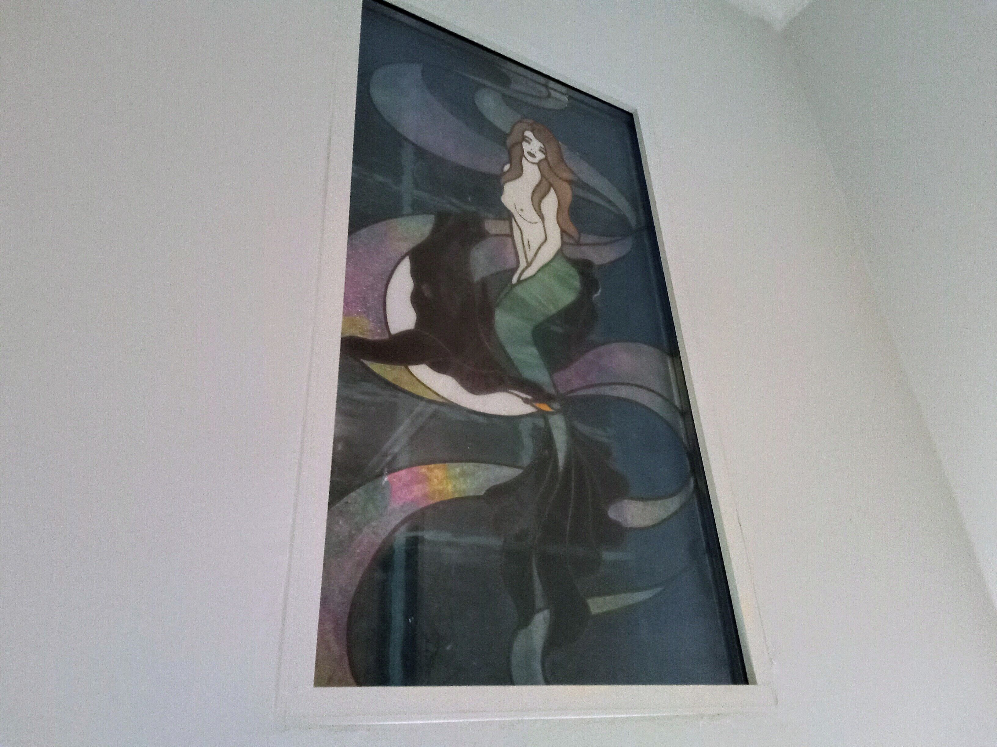 A framed artwork of a woman in a flowing dress on a white wall.