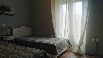 Une chambre avec deux lits, une table de chevet, une lampe et une fenêtre avec des rideaux.