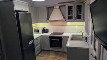 A compact kitchen with a refrigerator, microwave, toaster, sink, and cabinets.