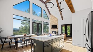 A modern kitchen with large windows, a central island, and a built-in fireplace. - BRAND NEW 4BR 4 BATH & BUNK ROOM MODERN MOUNTAIN LODGE WITH BEAUTIFUL VIEWS (Townsend)