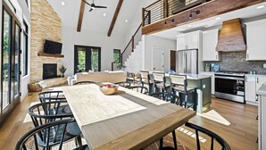 A spacious kitchen with a large island, wooden beams, and a stone fireplace. - BRAND NEW 4BR 4 BATH & BUNK ROOM MODERN MOUNTAIN LODGE WITH BEAUTIFUL VIEWS (Townsend)