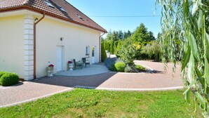 A single-story building with a tiled roof, a paved driveway, and a small patio area with outdoor seating. - Holiday apartment, 3 bedrooms, garden, Słowino (Slowino)