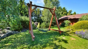 A wooden swing set in a garden with a house in the background. - Holiday apartment, 3 bedrooms, garden, Słowino (Slowino)