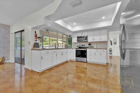 Kitchen features a large island with a sink and microwave, stainless steel appliances, and a window.