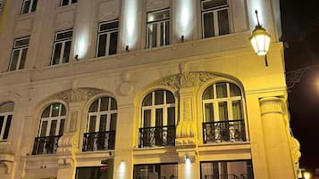 Un hotel de varios pisos con un estilo arquitectónico clásico, que presenta ventanas arqueadas y balcones.