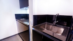 A compact kitchen with a black countertop, stainless steel sink, and a black backsplash. - Golden Lisbon Hotel (Lisbon)