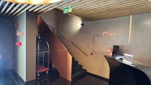 A modern hotel lobby with a reception desk, a staircase, and a large spherical light fixture. - Golden Lisbon Hotel (Lisbon)