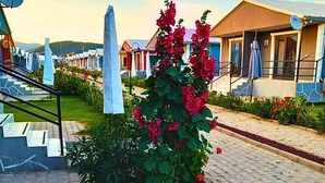 A residential area with houses, a garden with red flowers, a white obelisk, and a satellite dish. - Happy Life Houses (Seferihisar)