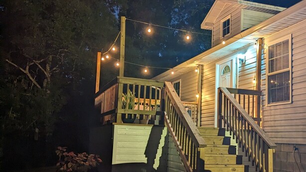 Una casa de madera con porche y escaleras, rodeada de árboles.