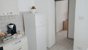 A modern kitchen with white cabinets, a built-in coffee maker, and a small potted plant. - La Casa di Katia (Canicatti)