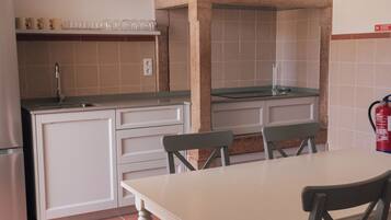 A kitchen with a dining table, chairs, a sink, and a stove.