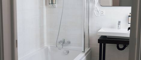 A modern bathroom with a glass-enclosed shower, a white sink, and a mirror above it.