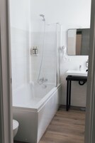 Un baño moderno con ducha de vidrio, un lavabo blanco y un espejo encima.