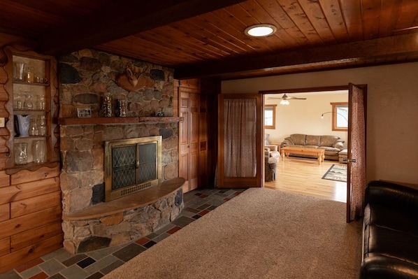 A cozy room with a stone fireplace, wooden walls, and a leather couch.