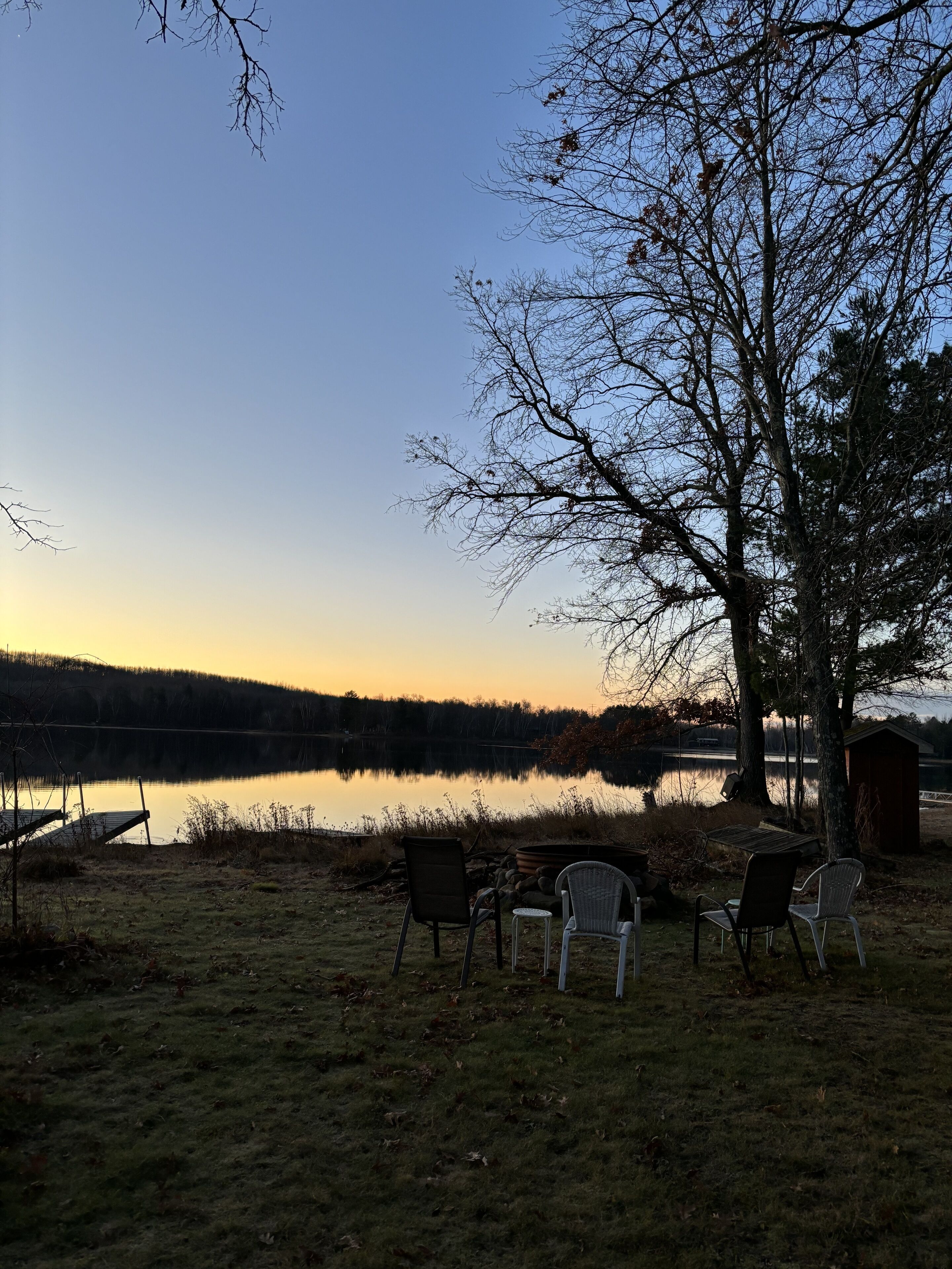 A lakeside view with chairs and a dock.