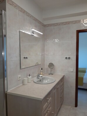 Features a large mirror above the sink, a handheld mirror, and a cabinet with drawers.