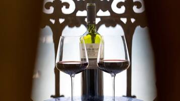 A bottle of wine and two glasses on a table with a decorative metal backdrop.